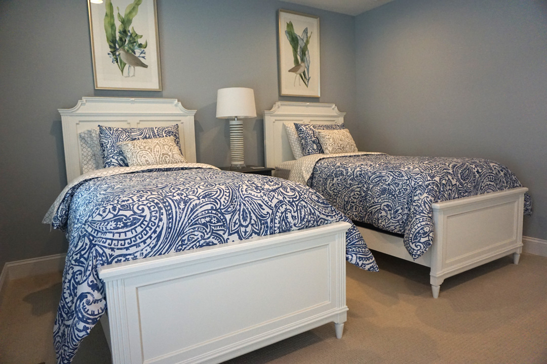 two beds in a bedroom with blue and white bedding