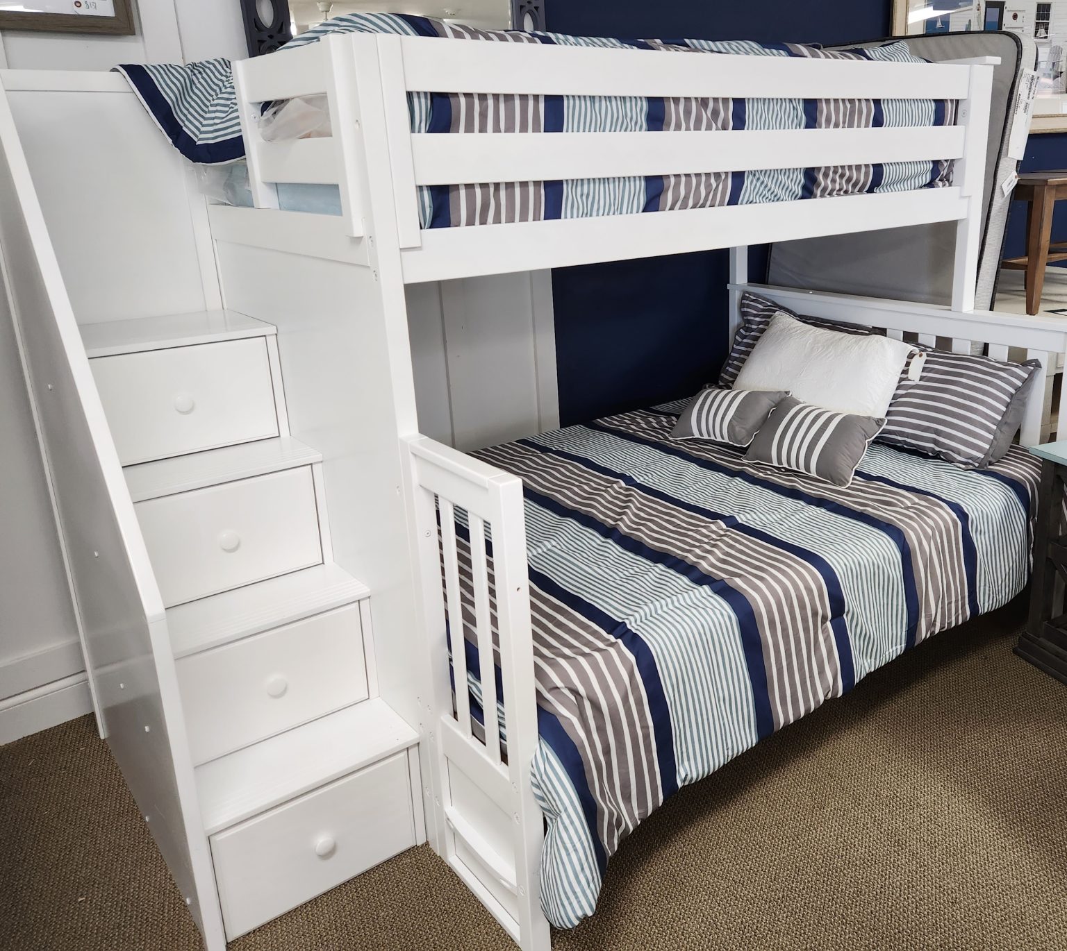 a white bunk bed with blue and white striped sheets