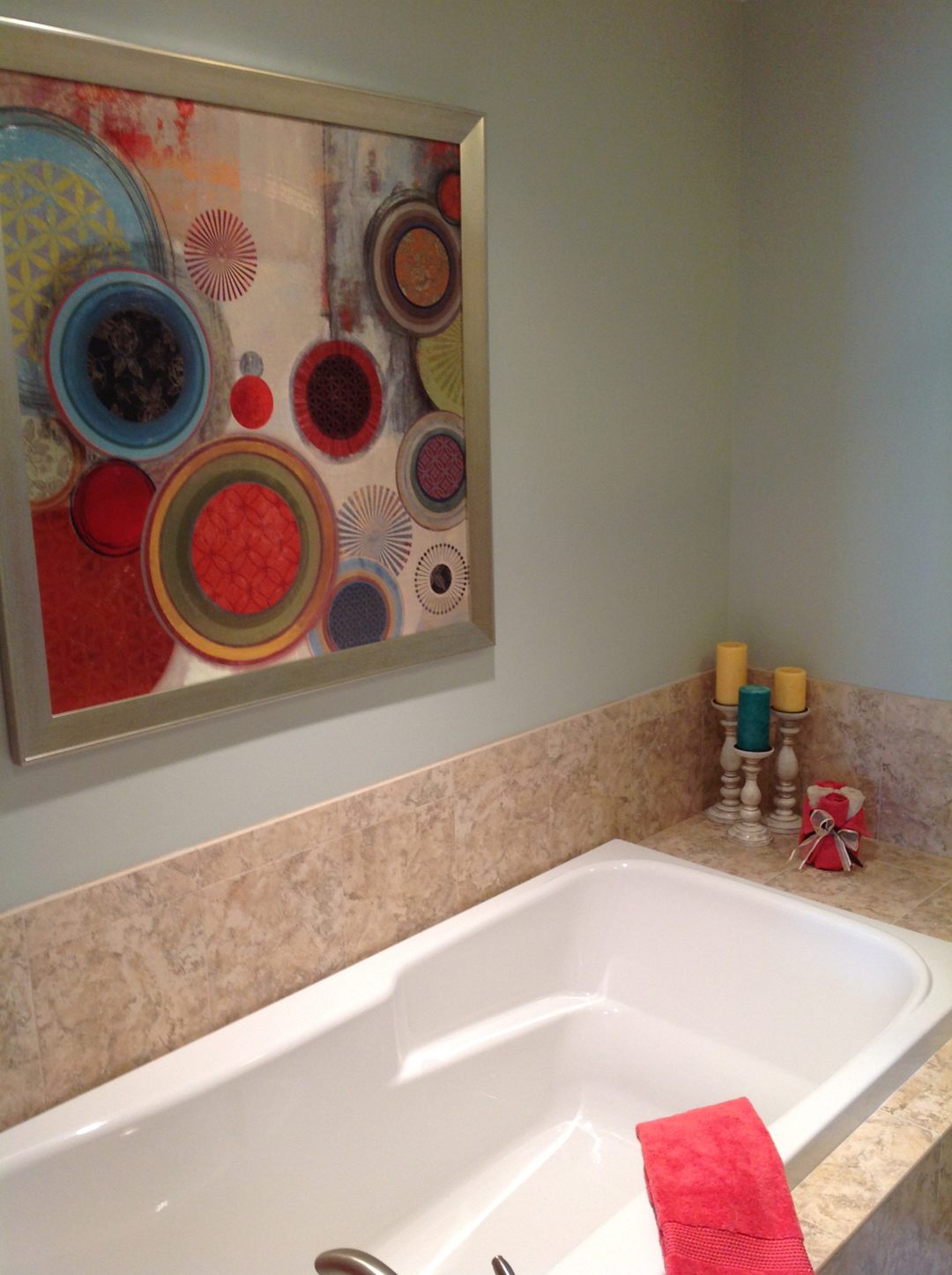 a bathroom with a white bathtub and a painting on the wall