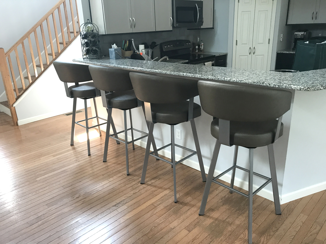 a kitchen bar with four stools in front of it