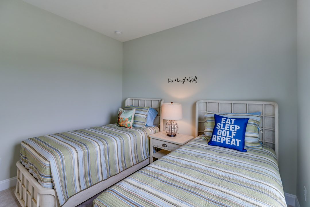 two beds in a bedroom with blue and green bedding