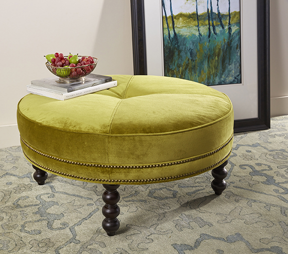 a green ottoman with wooden legs in a living room