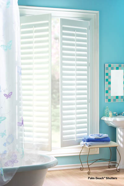 a bathroom with blue walls and white shutters