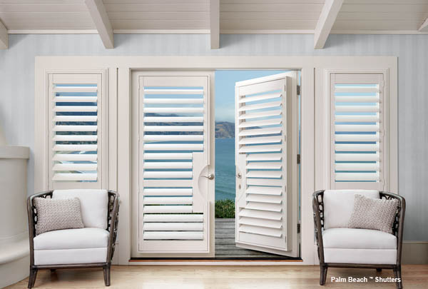 two white chairs sitting in front of open shutters