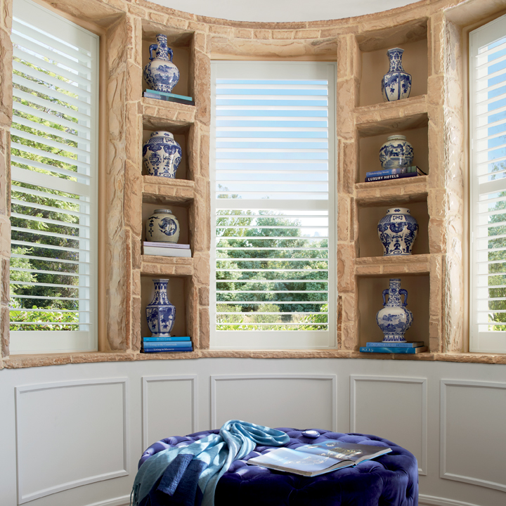 a window with shutters and shelves filled with blue and white vases