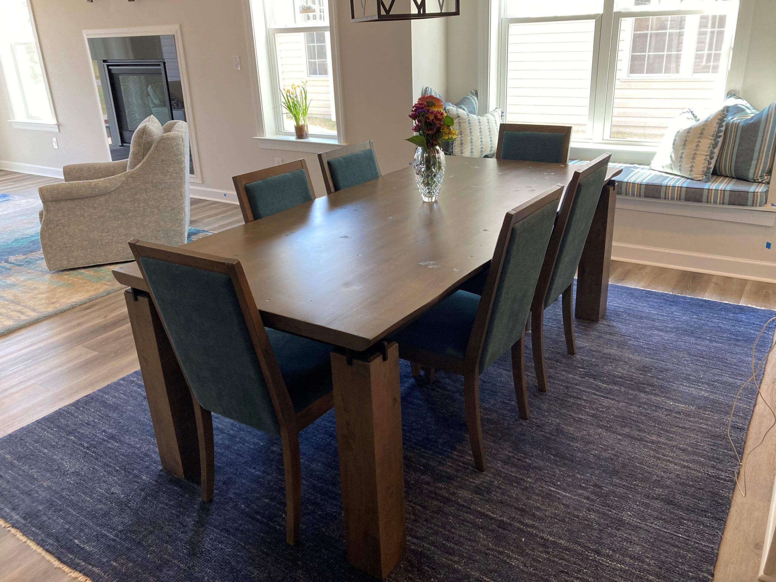 a dining room table with blue chairs and a rug on the floor