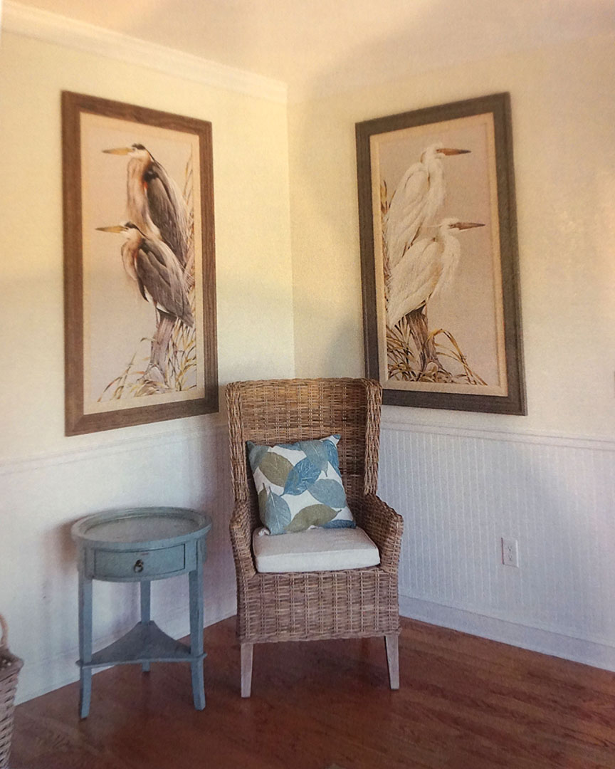 two paintings hang on the wall above a chair