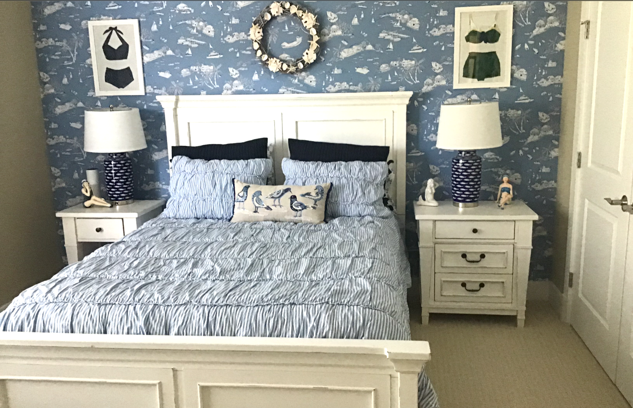 a bedroom with blue wallpaper and white furniture