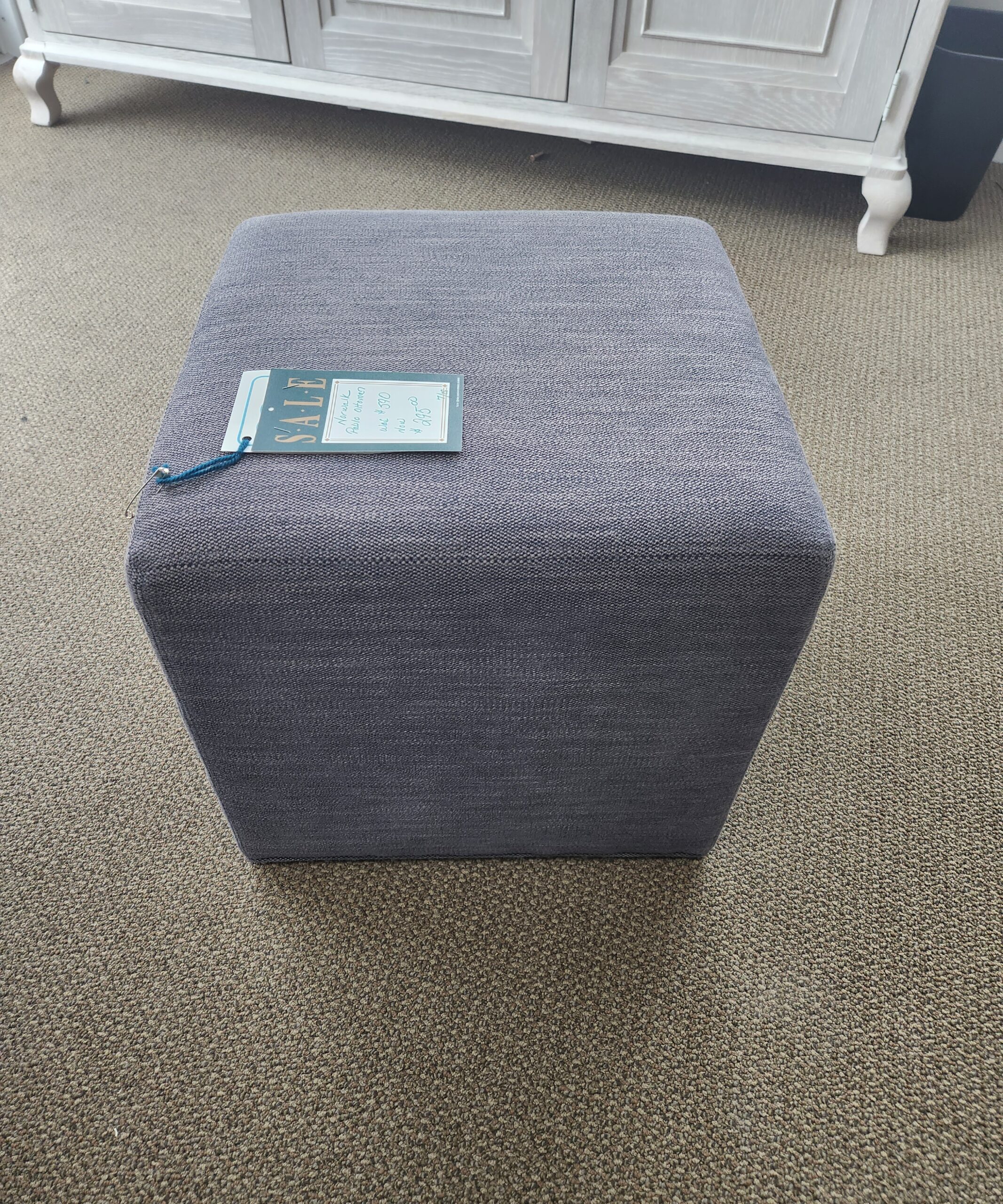 a gray ottoman with a blue tag on it
