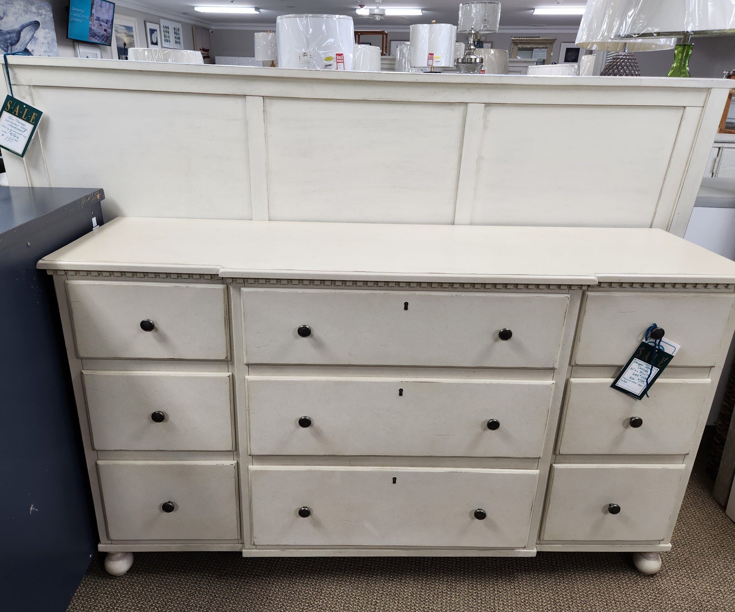 a white dresser sitting in a store next to a counter