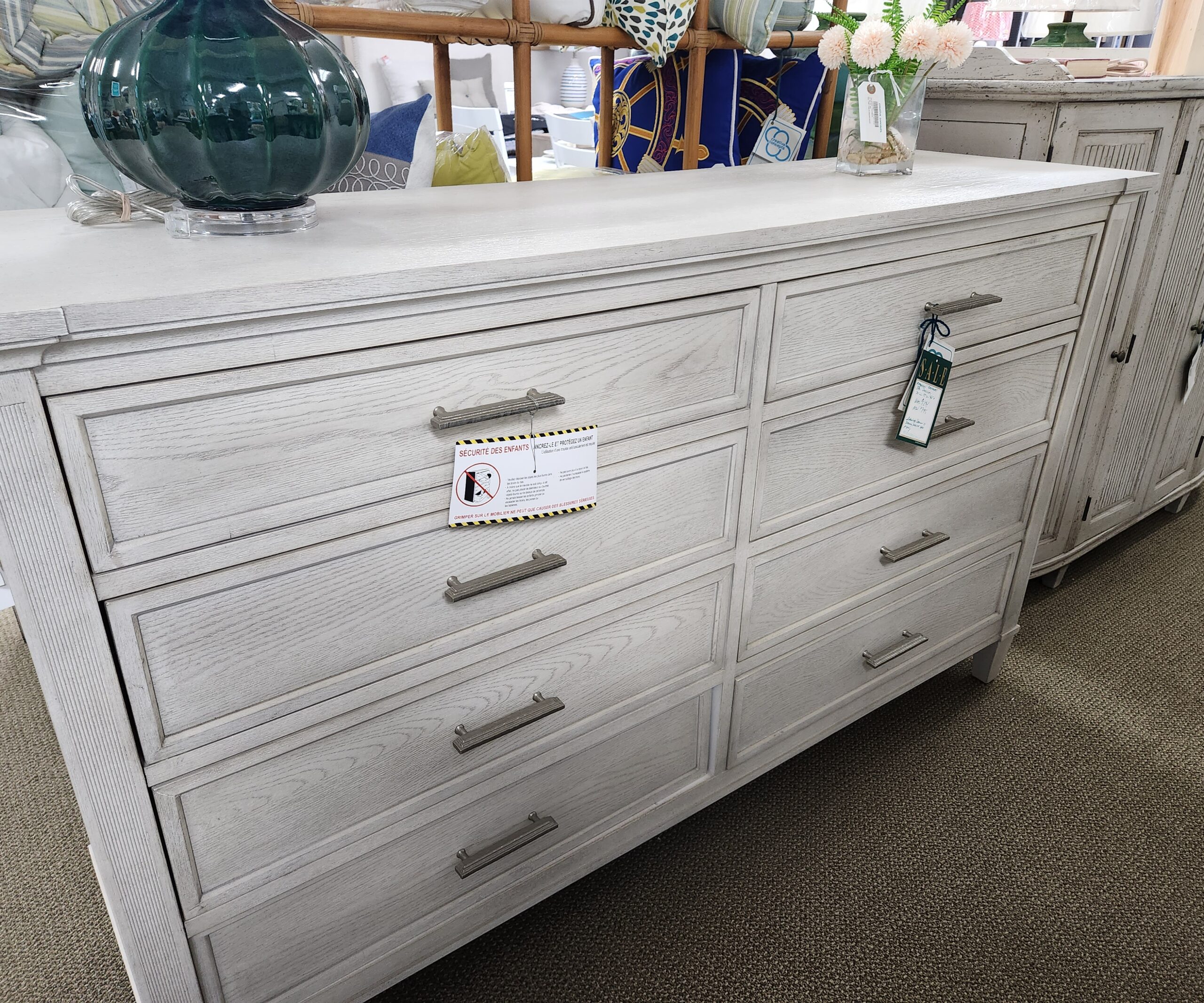 a white dresser with many drawers and vases on top