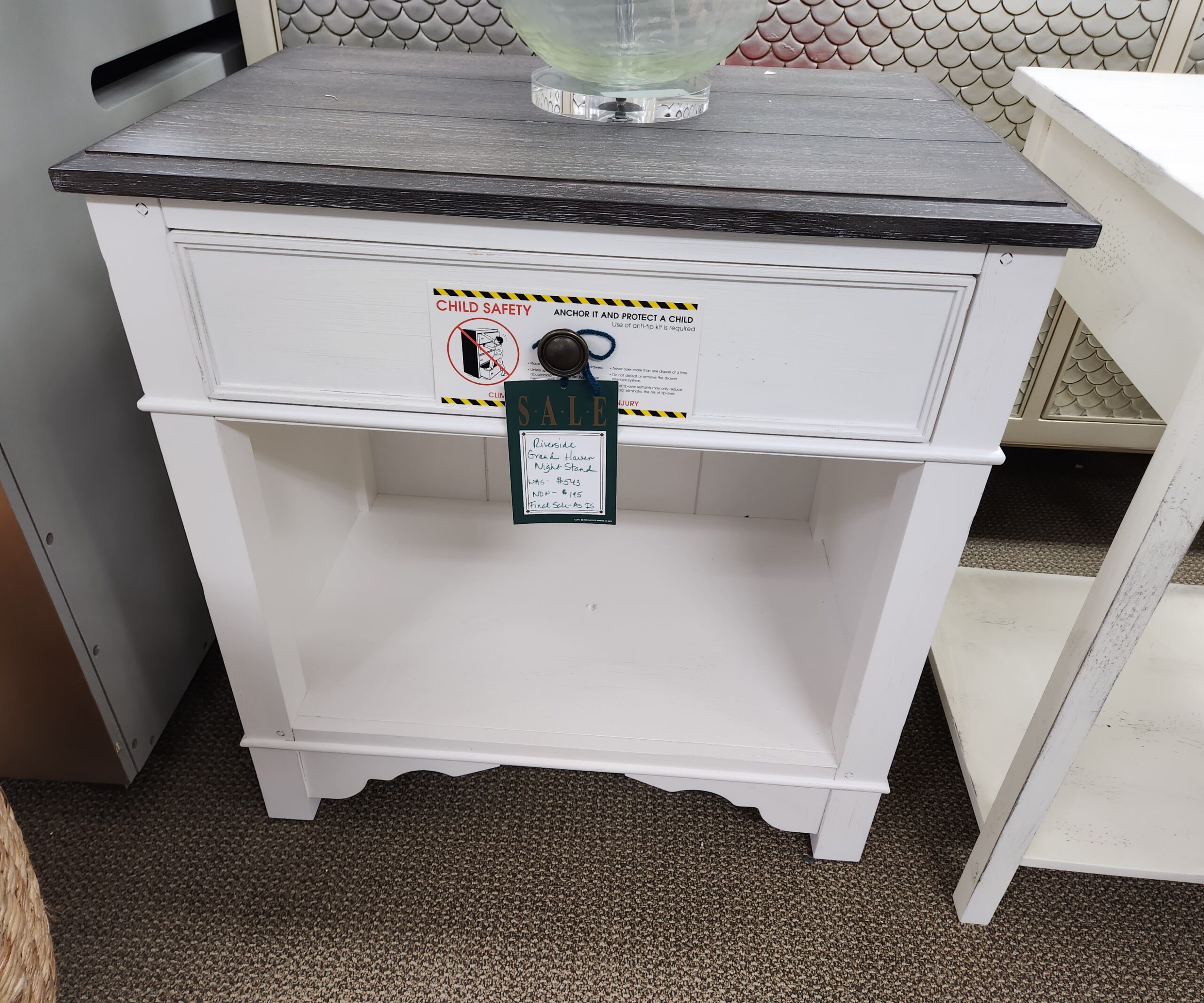 a small white cabinet with a glass vase on top