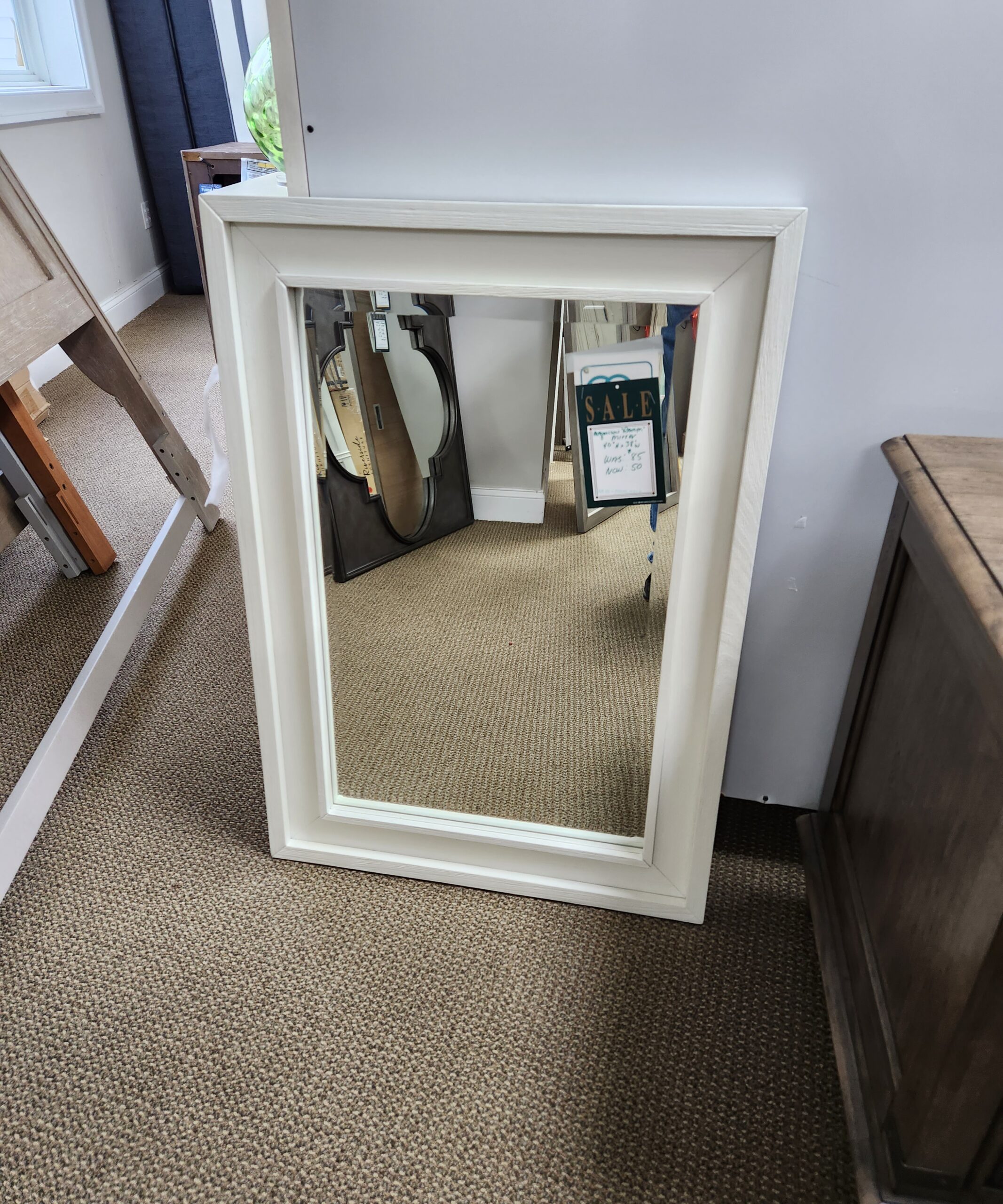 a white framed mirror hanging on the wall