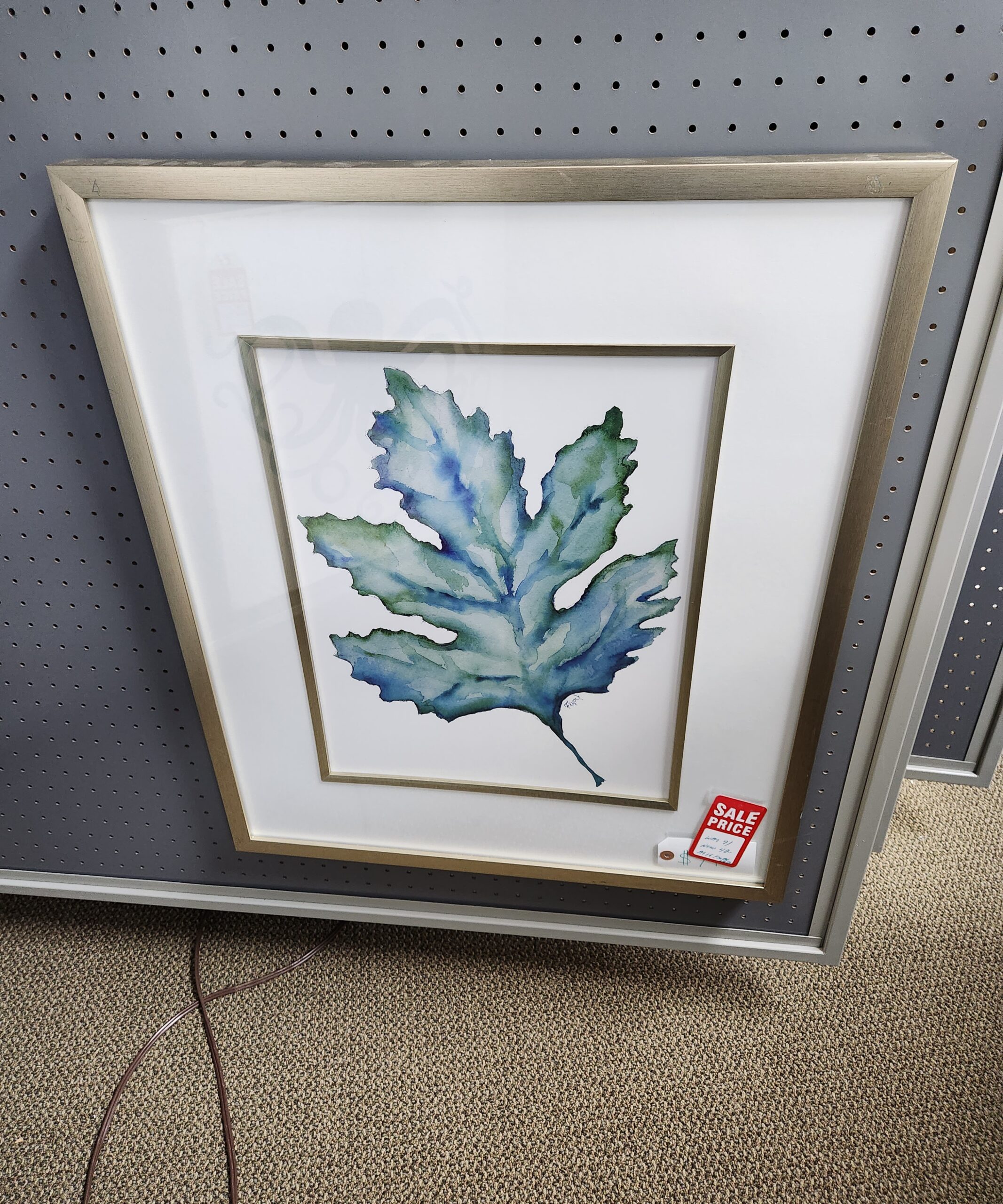 a painting of a leaf hangs on the wall