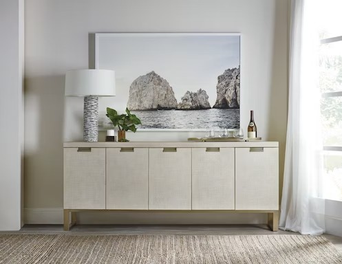 a white sideboard with a painting on the wall