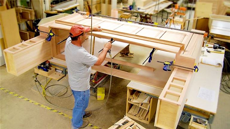 a man working on a wooden structure in a shop