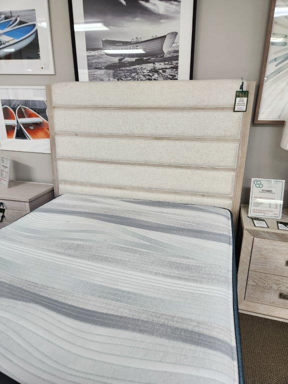 a bed with a white headboard and blue striped bedspread
