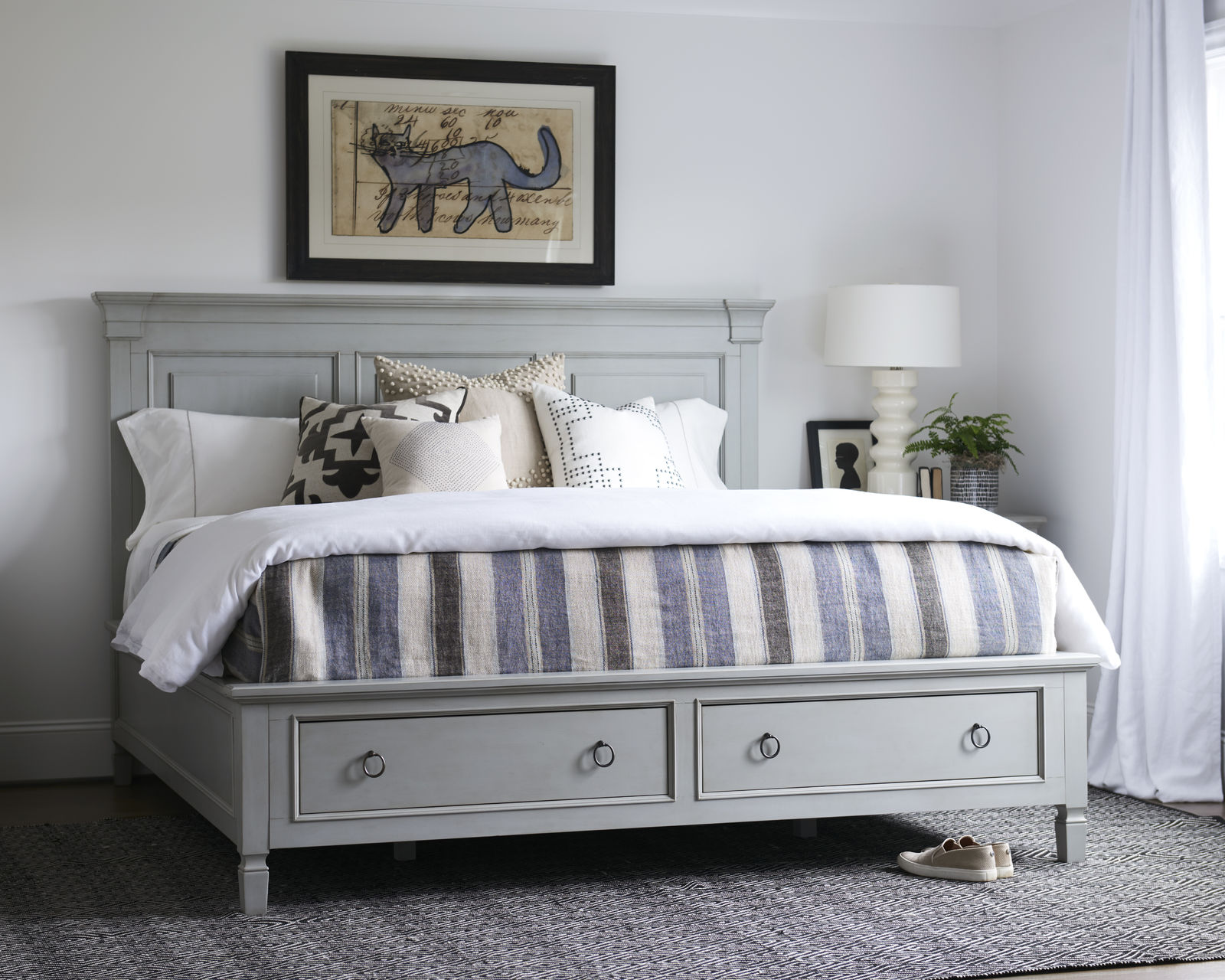 a bedroom with a bed, dressers and pictures on the wall