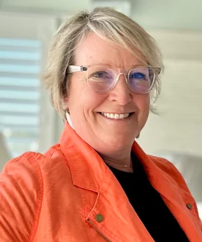 a woman wearing glasses and an orange jacket