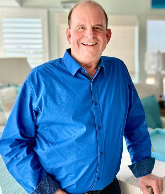 a man standing in front of a bed in a bedroom