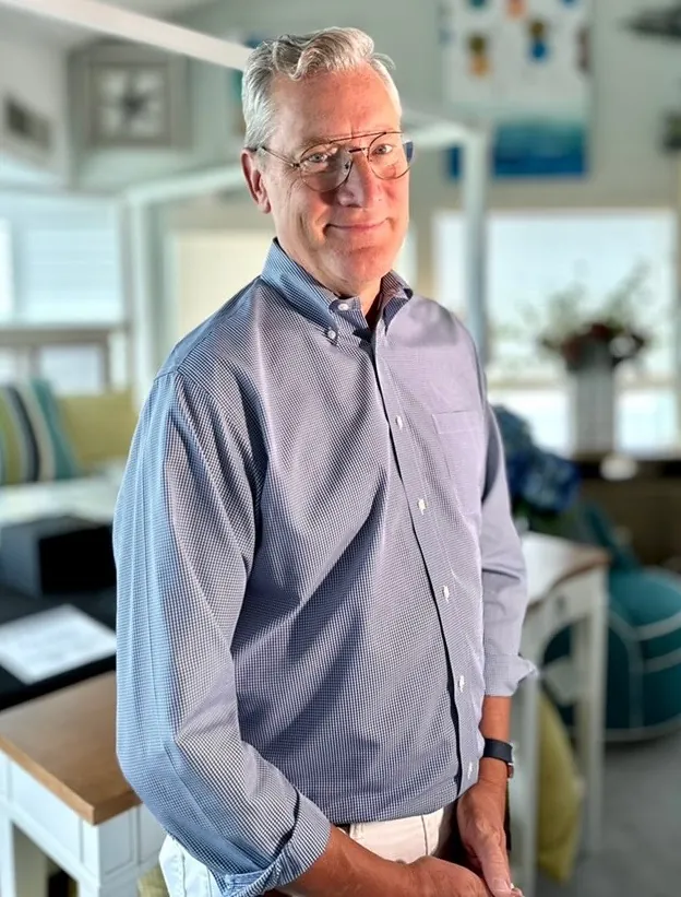 a man in a blue shirt and glasses standing in a room