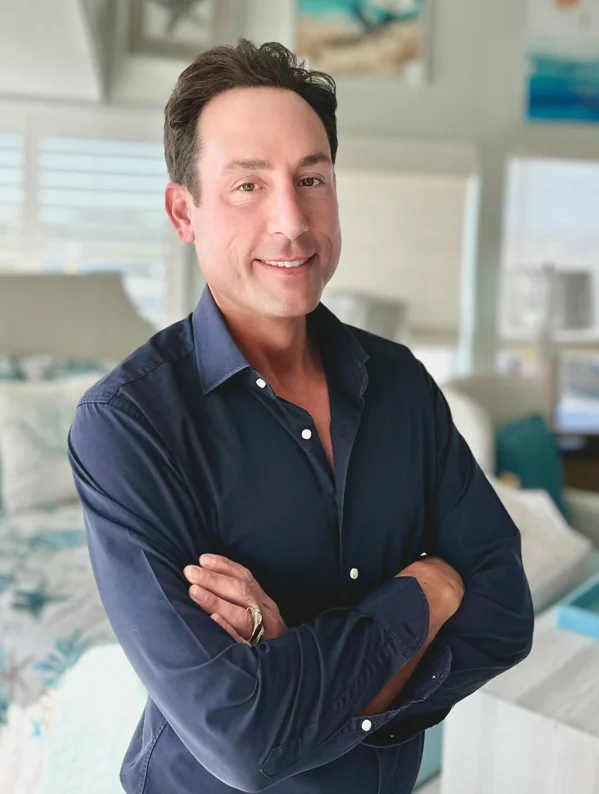 a man standing in front of a bed in a bedroom